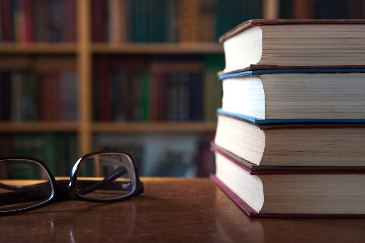 Stack of books with reading glasses resting on top