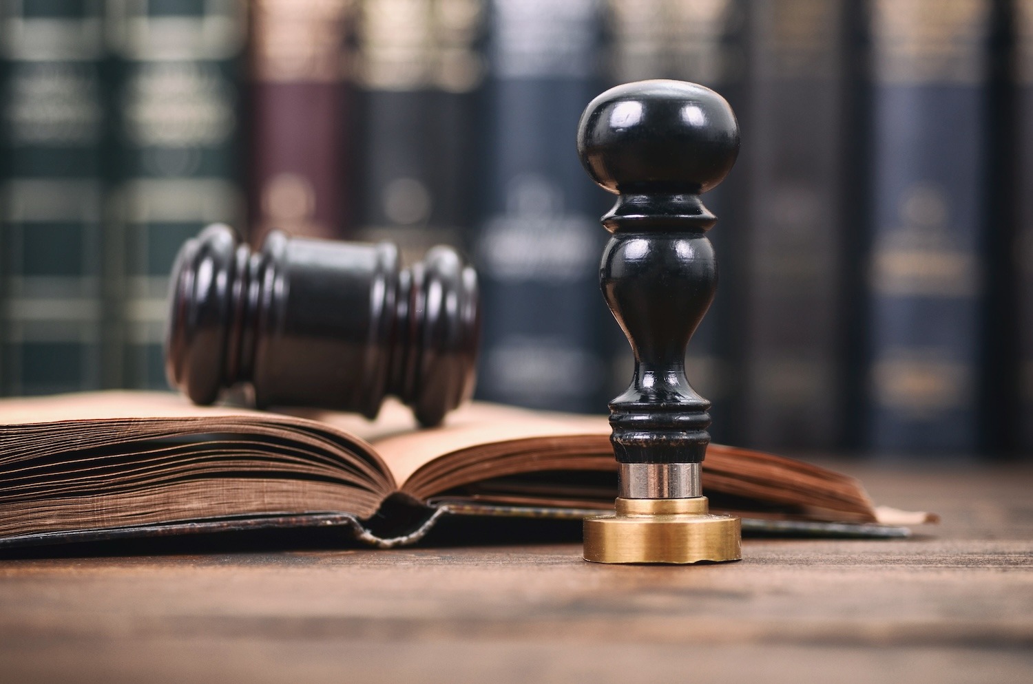 Legal books, open document, gavel and official stamp on a desk