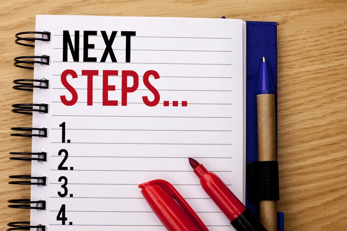 A notebook labeled “Next Steps” with a numbered list and writing tools beside it.