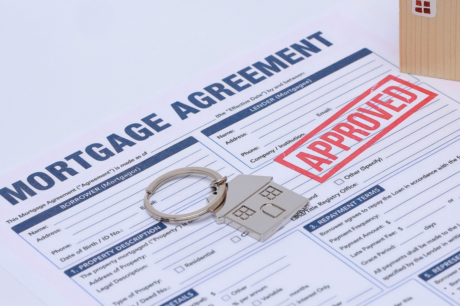 Mortgage agreement with an approved stamp, house key, and model house.