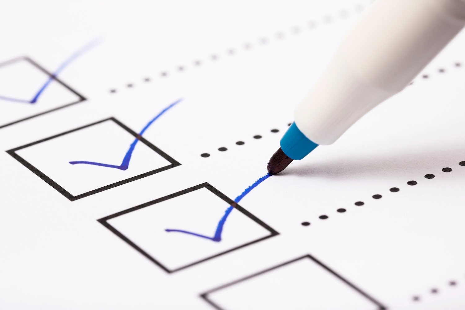 Close-up of a pen marking a checkbox on a printed checklist.