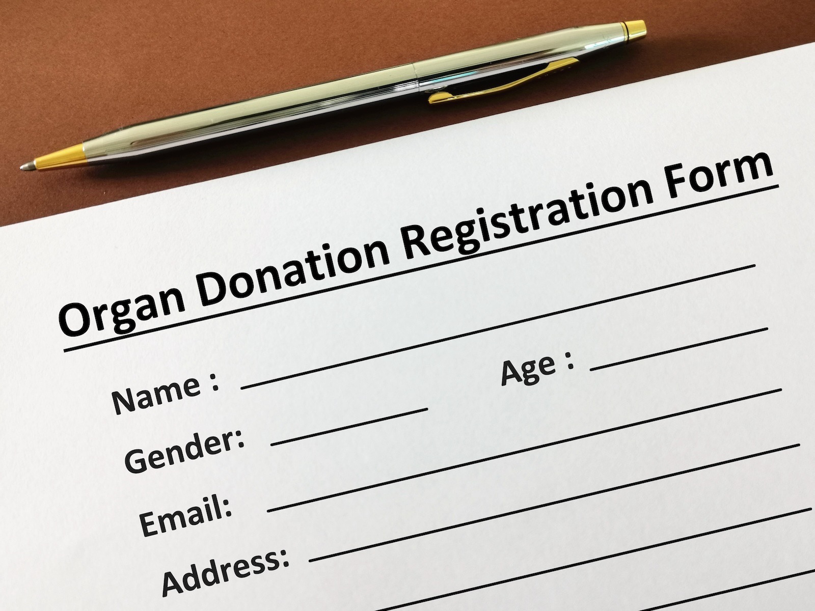 Estate Planning. Organ Donation. Funeral planning. Image of an organ donation registration form with registrant details to be completed. A pen for signing.