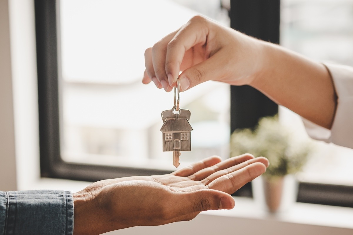 A close-up of one person handing a set of house keys to another person.