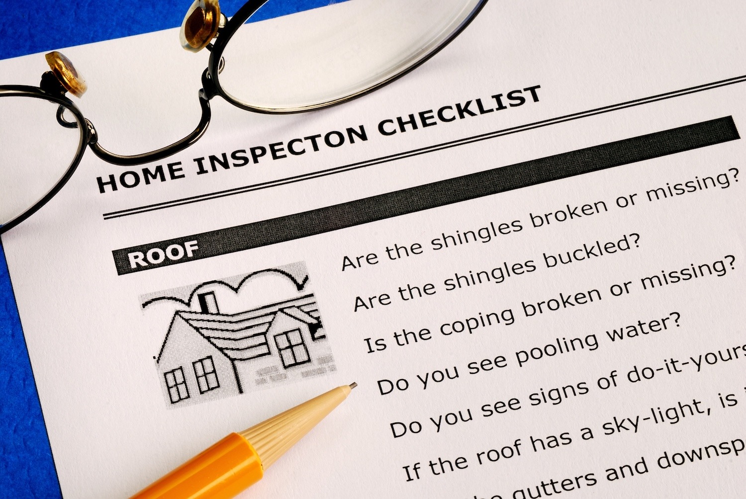 Home inspection checklist with a pencil and eyeglasses resting on the inspection document.