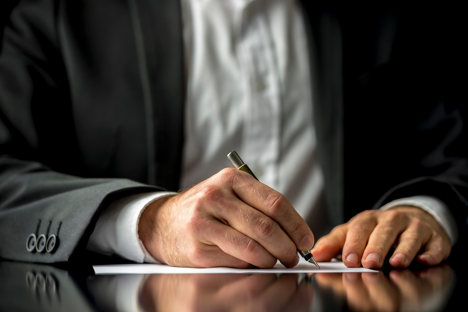 First Time Executor. image of a man's hands with a pen signing a document on a desk.